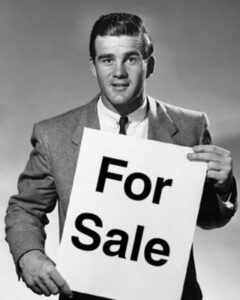 Man holding a 'For Sale' sign